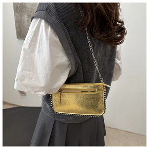 Detail of metallic gold shoulder bag featuring silver stud trim and chain strap