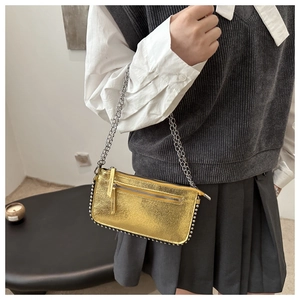 Detail of metallic gold envelope bag featuring silver bead trim and a sleek chain strap