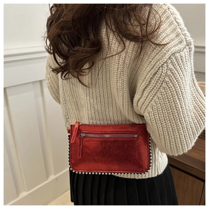 Close-up of red metallic crossbody bag with silver rivet details and chain strap