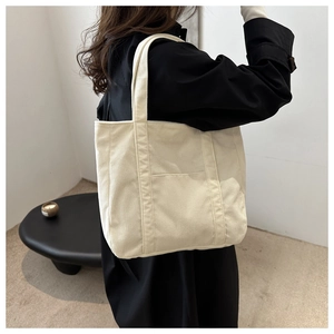Close-up of off-white corduroy tote bag showing textured fabric and front patch pocket