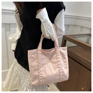 Pink corduroy tote bag detail showing large capacity and textured fabric on female model