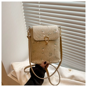 Gros plan d'un sac en paille beige avec broderie florale rose et fermoir en métal doré