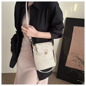 Dettaglio borsa a tracolla intrecciata beige con ricamo floreale e chiusura dorata