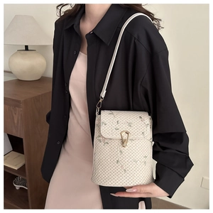 Détail du sac bandoulière en paille avec broderie florale et fermoir en métal doré