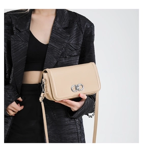 Detail of apricot crossbody bag with silver double-ring buckle on a black blazer