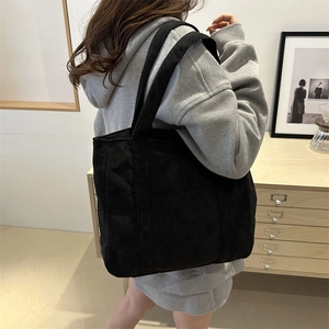 Black corduroy tote bag for women showing a large capacity shoulder strap design on a model