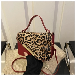 Détail du sac à main en cuir rouge avec rabat imprimé léopard et garniture en métal doré