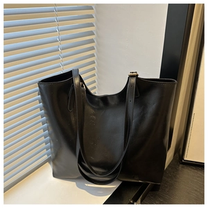 Macro shot of large black oil wax leather tote bag with long straps for commute