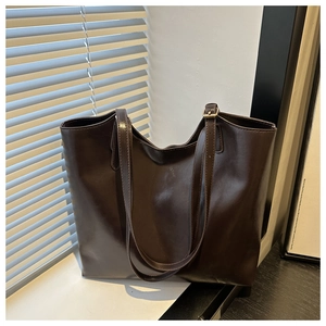 Detail of dark brown wax leather tote bag featuring adjustable shoulder strap and hardware