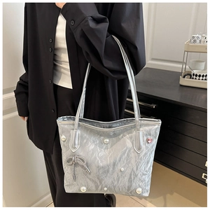 Détail du sac cabas plissé argenté avec perles et breloque noeud en strass brillant