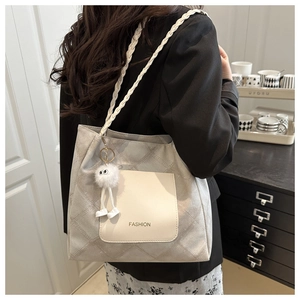 Detail of light grey quilted tote bag with woven handle and plush charm accessory