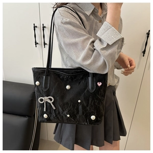 Détail du sac cabas en velours noir avec décorations en perles et pendentif nœud