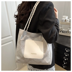 Detail view of grey quilted tote bag with white front pocket and braided shoulder straps