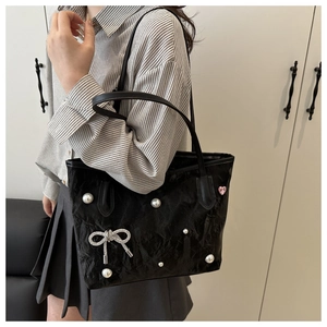 Détail d'un sac cabas noir texturé orné de perles et d'un nœud en strass chic
