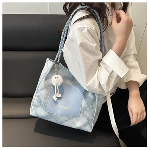 Detail of light blue woven handle tote bag with quilted pattern and plush charm