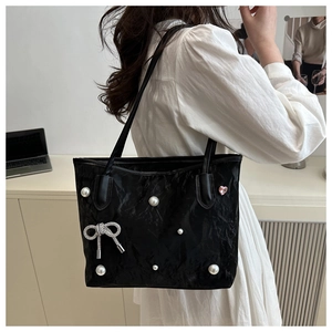 Détail du sac cabas noir avec perles, nœud en strass et petit détail en cœur rose