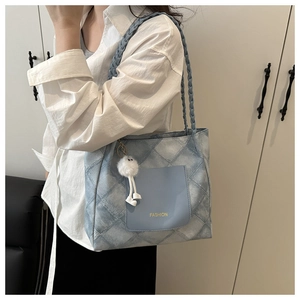 Blue quilted tote bag with woven strap and fashion pocket shown on model shoulder