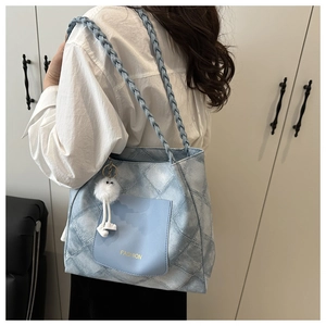 Detail of blue quilted tote bag with woven shoulder strap and cute plush charm pendant
