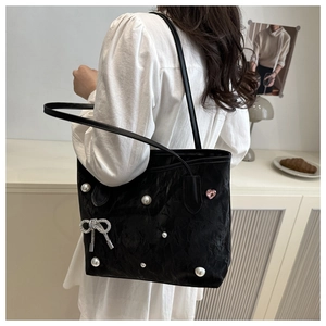 Détail du sac cabas plissé noir avec des perles et un nœud en strass élégant
