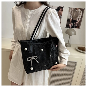 Détail d'un sac cabas plissé noir avec perles, nœud en strass et pendentif cœur