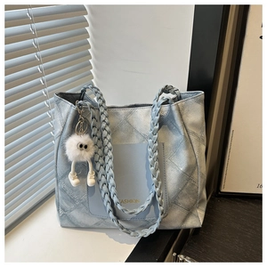 Detail of light blue quilted tote bag with woven handles and fashion lettering