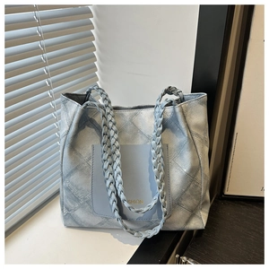 Close-up of light blue quilted tote bag featuring woven straps and fashion print pocket