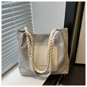 Detail of quilted grey tote bag with braided cream leather strap and Fashion text