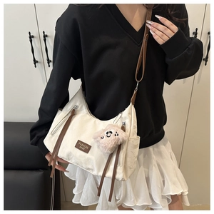 Detail of white tote bag featuring side zipper pockets and brown fashion leather tag