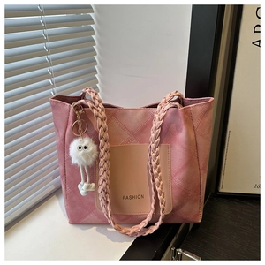 Detail of pink tote bag showing quilted texture, woven handle, and cute plush charm