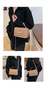 Close-up of khaki leather handbag featuring a golden turn-lock clasp and shoulder strap