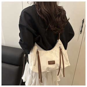 Detail of minimalist cream tote bag with brown leather tassels and fashion branding
