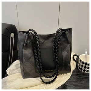 Detail of grey tote bag featuring diamond texture and woven leather handles