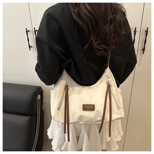 Detail of off-white hobo shoulder bag with brown leather strap and brand label on a model