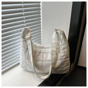 Detail of white quilted tote bag with colorful stitching and adjustable shoulder strap
