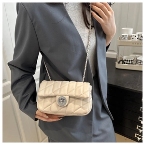 Détail du sac matelassé crème avec bandoulière chaîne argentée et fermoir rotatif en métal