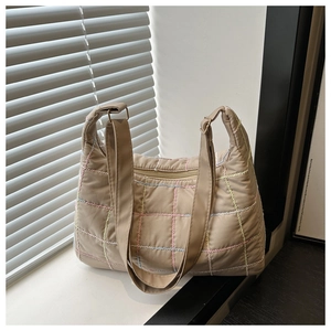 Detail of quilted tote bag featuring multi-colored embroidery and soft padded texture