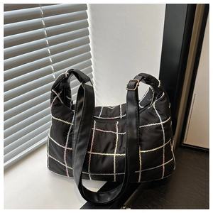 Detail of black tote bag with colorful hand-stitched grid pattern and wide shoulder strap