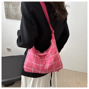 Detail of rose pink quilted tote bag with white stitching on a model in a black blazer