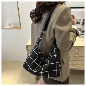 Detail of the colorful plaid embroidery and leather strap on this large black tote bag