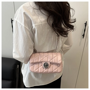 Détail du sac à bandoulière matelassé rose avec chaîne argentée porté sur une chemise
