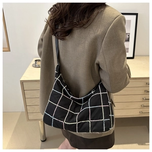 Detail of black quilted hobo bag with colorful stitching shown on model shoulder