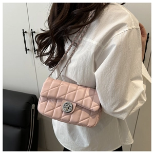 Side view of a light pink quilted crossbody bag with silver chain strap on model