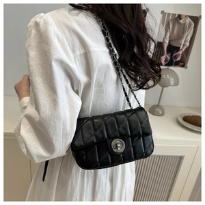 Detail of a black quilted leather crossbody bag with chain strap and twist-lock closure