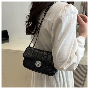 Close-up of black quilted leather shoulder bag featuring silver chain and round twist lock