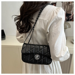 Close-up of classic quilted rhombic pattern and silver twist lock on black shoulder bag