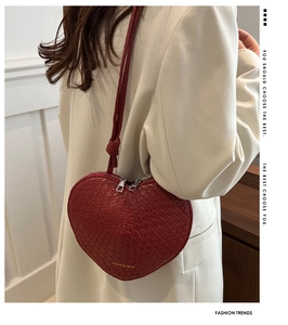 Detail of red heart-shaped woven leather bag with dual zippers and gold lettering