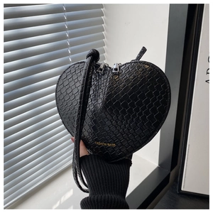 Detail of heart-shaped crossbody bag with crocodile embossing and golden lettering