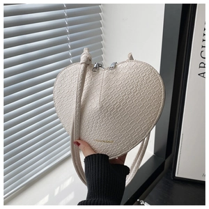 Detail of cream white heart-shaped bag with faux crocodile texture and gold zipper