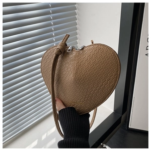 Detail of khaki heart-shaped crossbody bag featuring crocodile pattern and double zipper