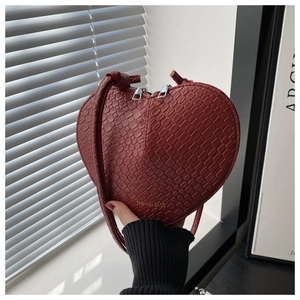 Close-up of wine red heart-shaped crossbody bag with crocodile embossed leather texture